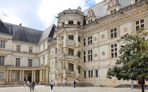 Royal Blois Castle exterior with visitors in courtyard, France.