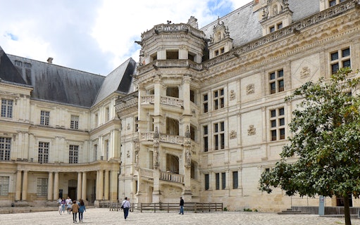 Royal Blois Castle exterior with visitors in courtyard, France.