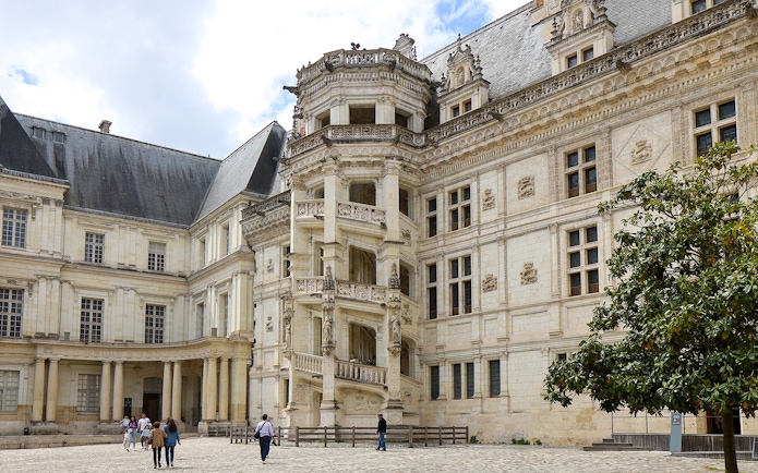 Royal Blois Castle exterior with visitors in courtyard, France.