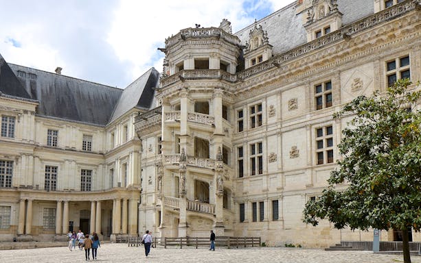 Royal Blois Castle exterior with visitors in courtyard, France.