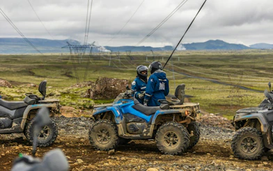 ATV riders on Twin Peaks tour with mountain and lake views near Reykjavik.
