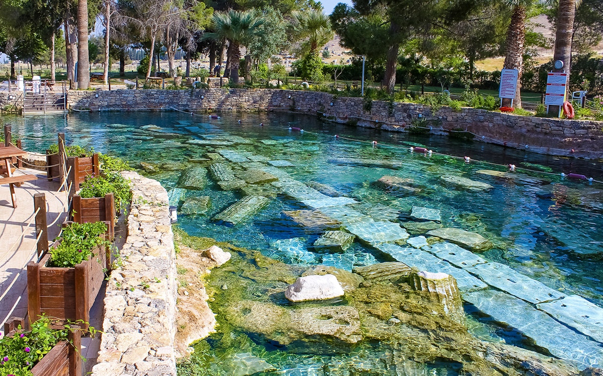 Cleopatra pool in Pamukkale with submerged ancient columns and clear turquoise water.