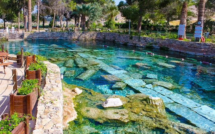 Cleopatra pool in Pamukkale with submerged ancient columns and clear turquoise water.