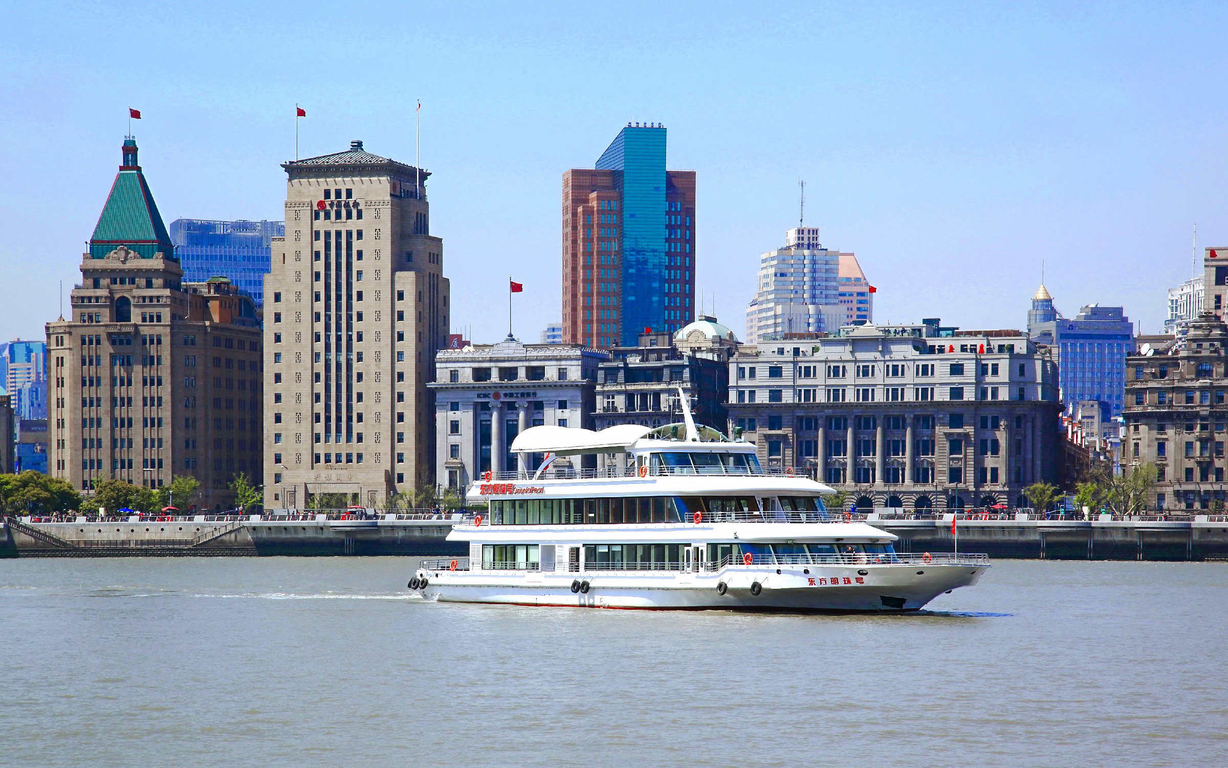 Cruise ship on Huangpu River with Shanghai skyline in the background.