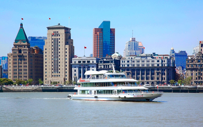 Cruise ship on Huangpu River with Shanghai skyline in the background.