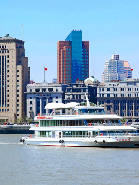 Cruise ship on Huangpu River with Shanghai skyline in the background.
