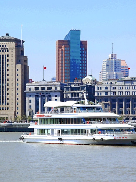 Cruise ship on Huangpu River with Shanghai skyline in the background.