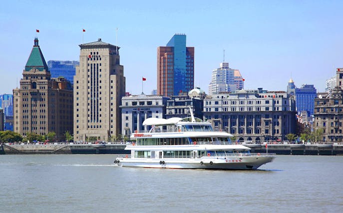 Cruise ship on Huangpu River with Shanghai skyline in the background.