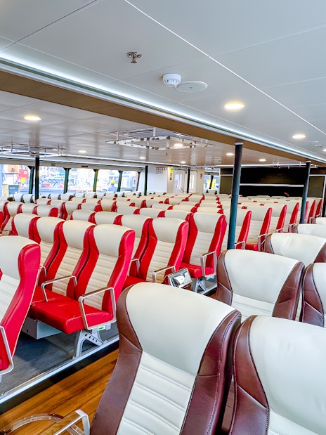 Ferry interior with rows of red and white seats, Singapore to Batam route.