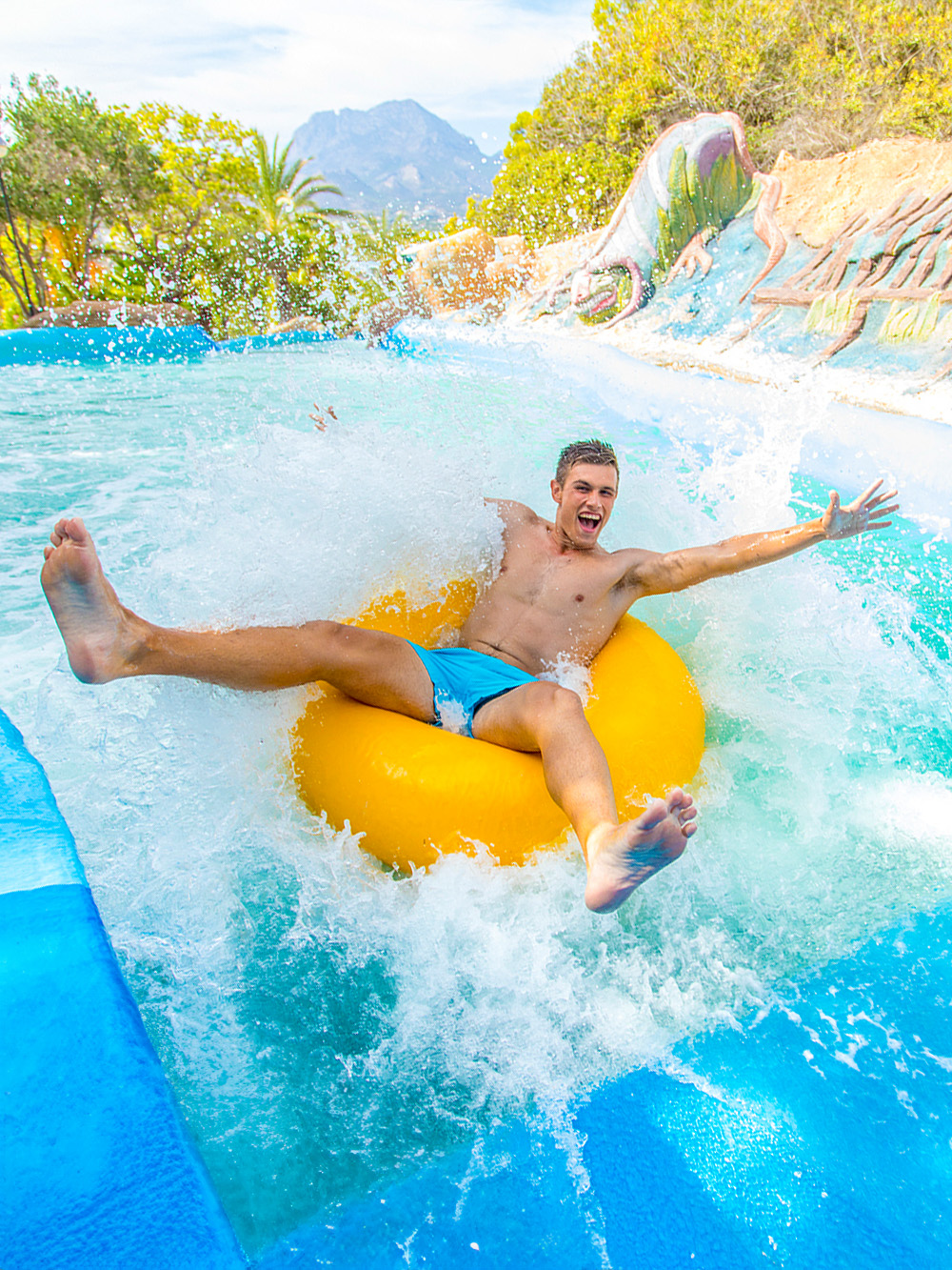 Person enjoying a water slide on a yellow tube at Aqualandia.