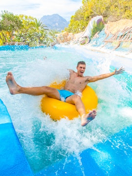 Person enjoying a water slide on a yellow tube at Aqualandia.