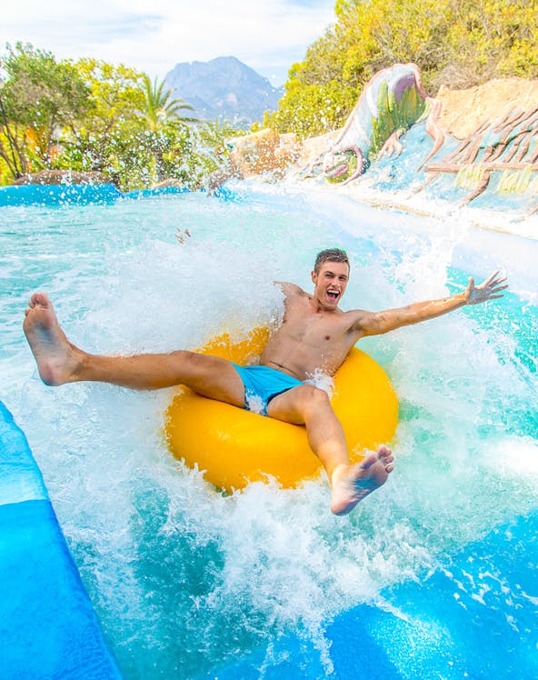 Person enjoying a water slide on a yellow tube at Aqualandia.