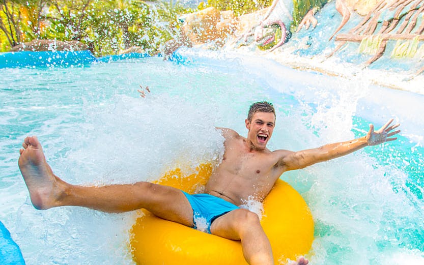 Person enjoying a water slide on a yellow tube at Aqualandia.