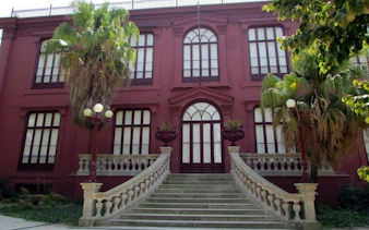 Elegant red building with arched windows and palm trees, Porto city exploration game.