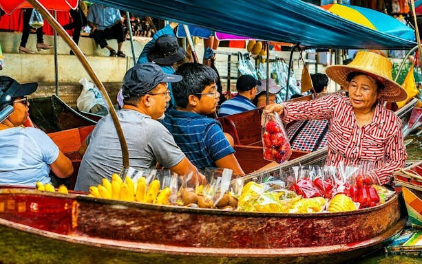 Vendors selling fruits from boats at a bustling floating market.
