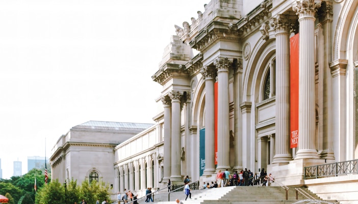 The Metropolitan Museum of Art exterior in New York with visitors on the steps.