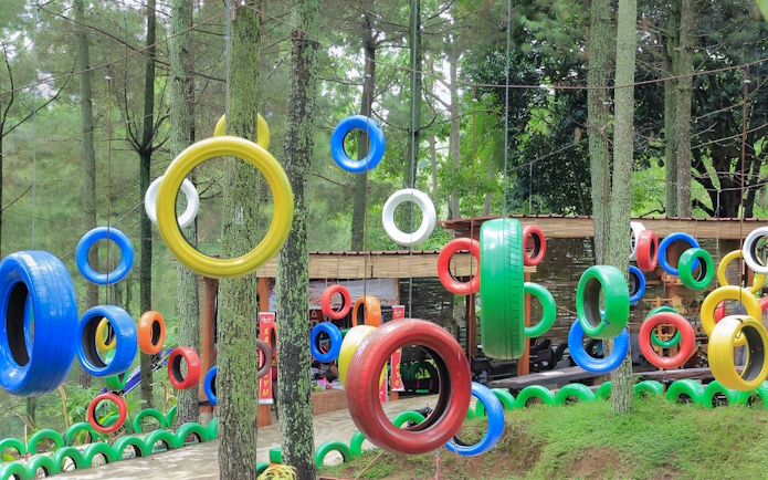 Colorful tire swings at Dago Dreampark entrance in Bandung forest setting.