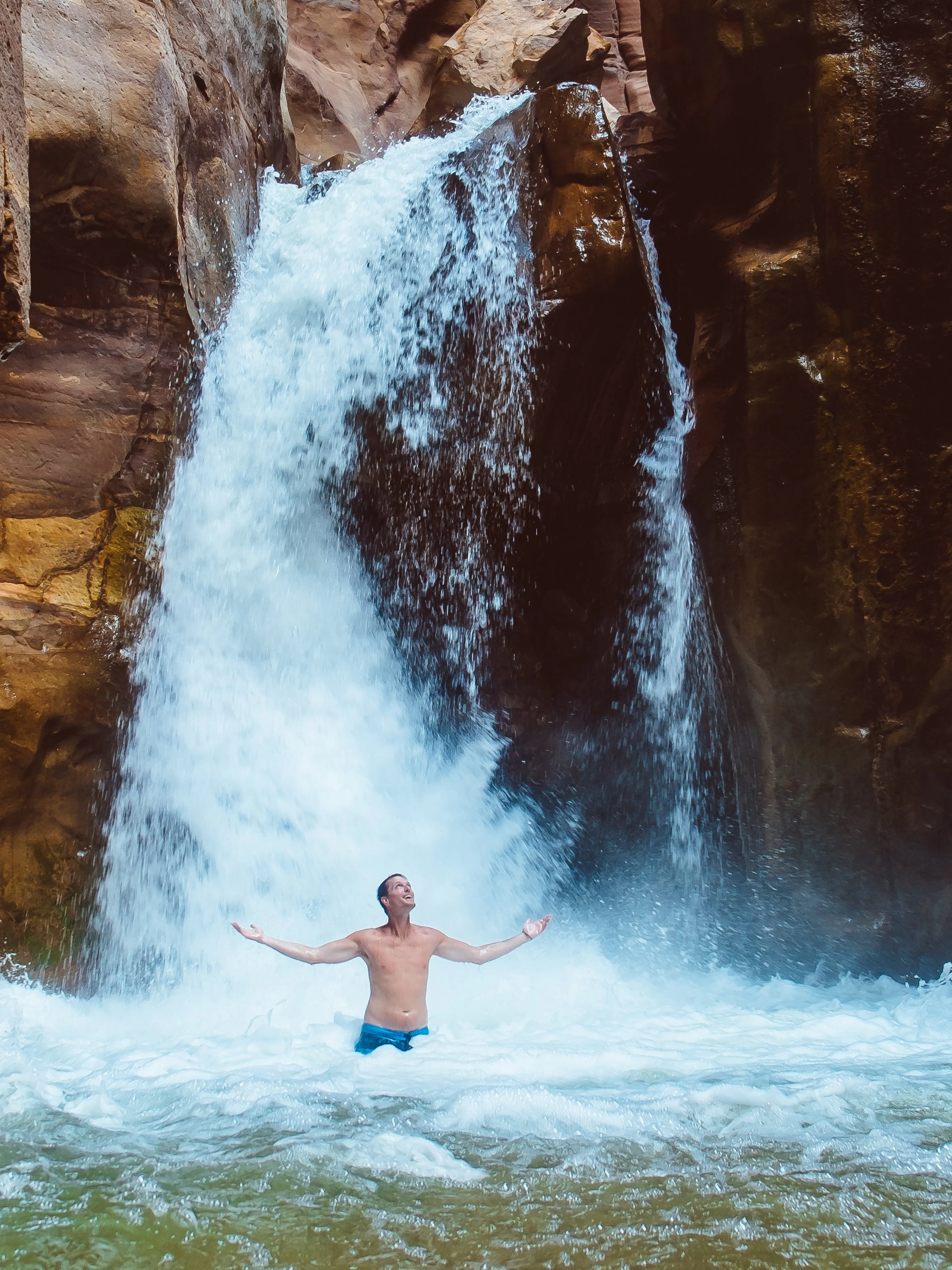 Man enjoying waterfall in Wadi Mujib, Jordan.