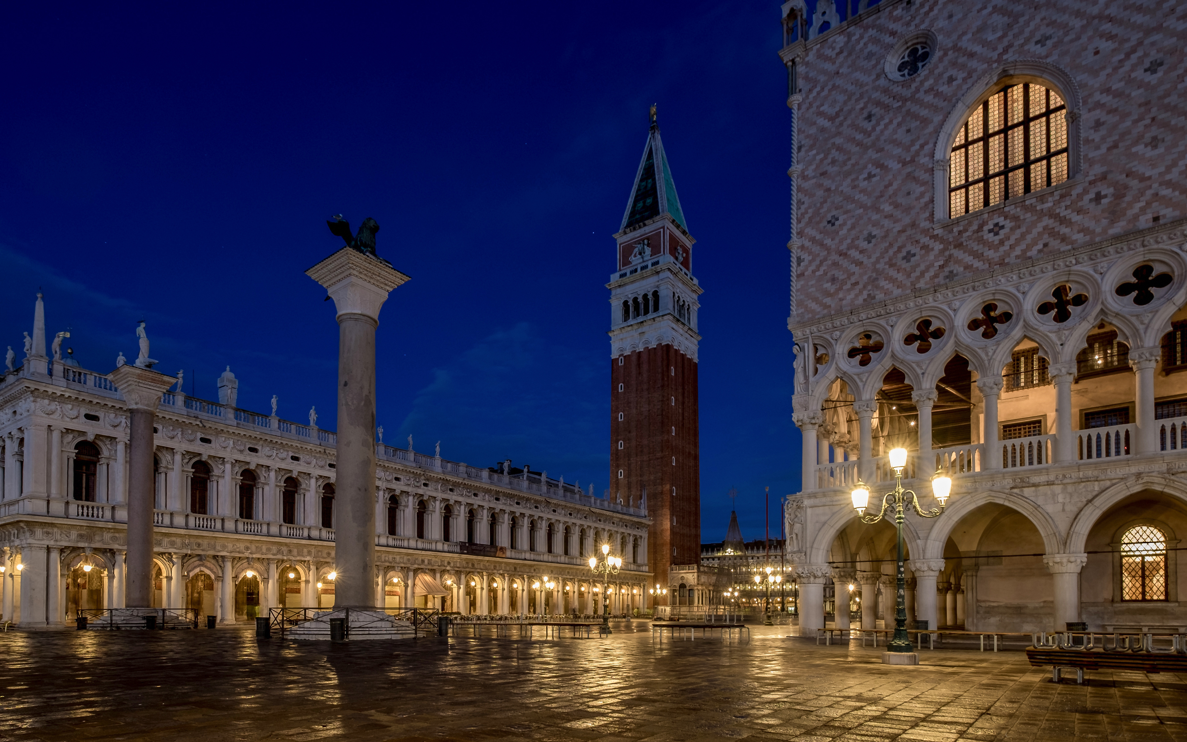 San Marco Square in Venice at night with illuminated buildings and bell tower.
