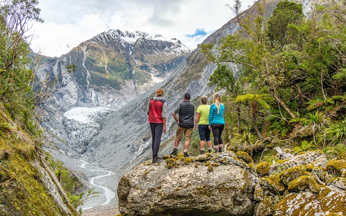 Tourists viewing Fox Glacier Valley landscape in New Zealand.
