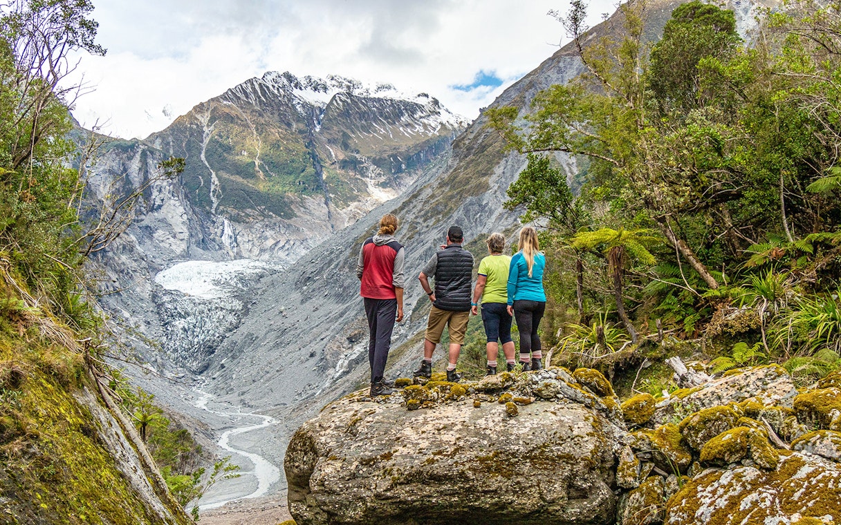 Tourists viewing Fox Glacier Valley landscape in New Zealand.