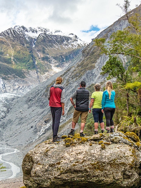 Tourists viewing Fox Glacier Valley landscape in New Zealand.