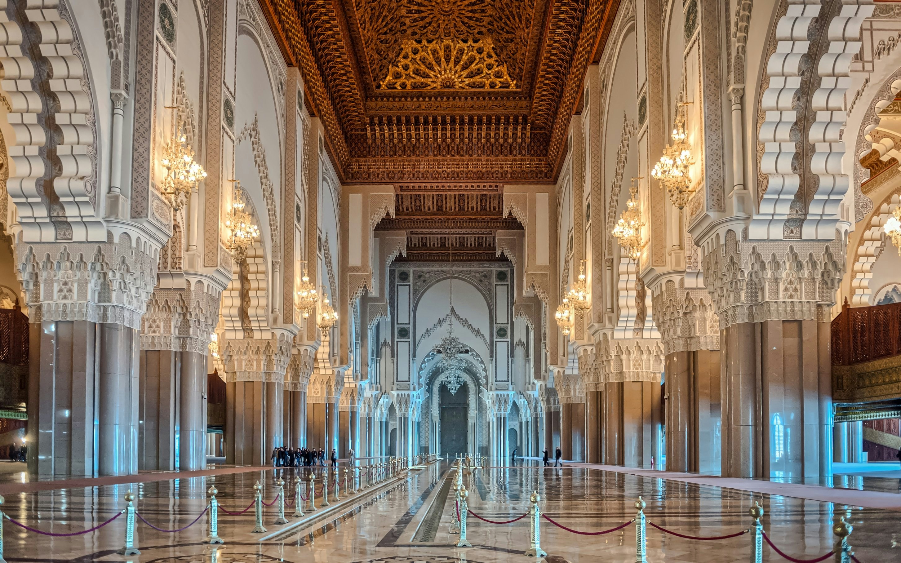 Internal corridor of Hassan II Mosque with ornate arches and chandeliers, Casablanca, Morocco.