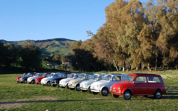 Vintage cars lined up for The Godfather Tour from Catania, set against a scenic landscape.