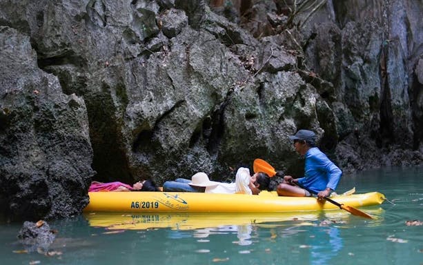 Canoe tour through limestone caves in Phuket with guide paddling.