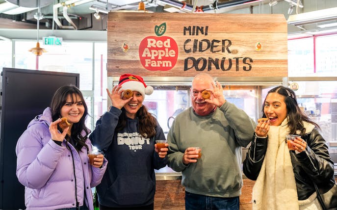 Visitors enjoying mini cider donuts at Red Apple Farm during a guided donut tour in Boston.