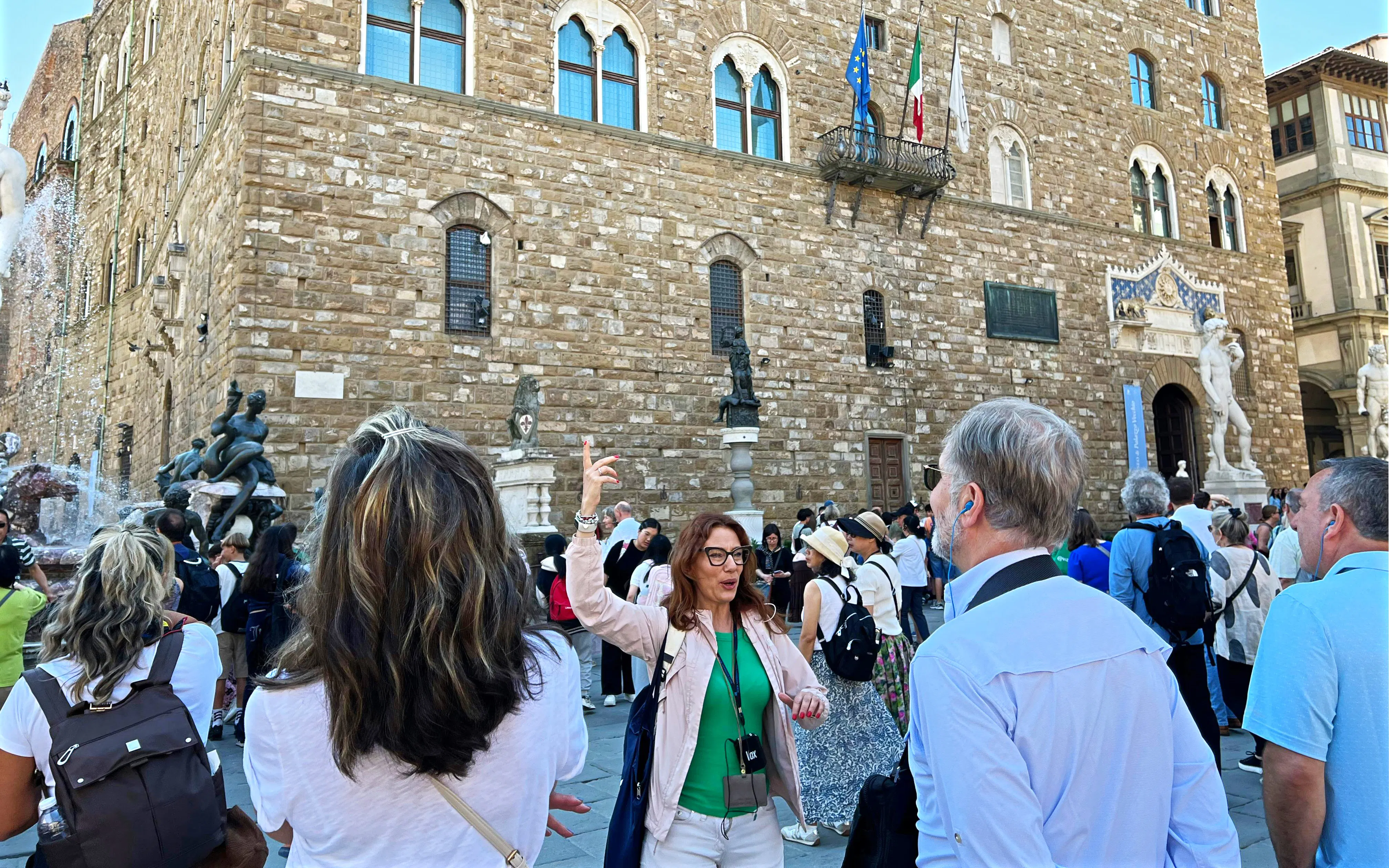 Tour group in front of Palazzo Vecchio, Florence, with guide explaining historical details.