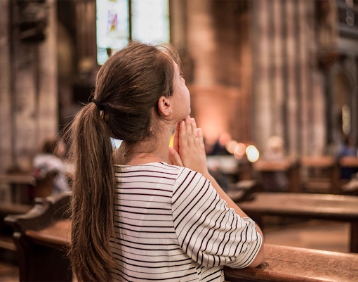 Woman praying in peaceful Hampton chapel during a spiritual tour