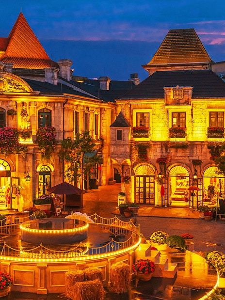 Central square in medieval French village at Ba Na Hills Park, Da Nang, illuminated at dusk.