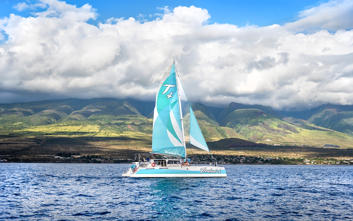 Sailboat on Luxury West Snorkel Sail Tour in Maui, Hawaii with lush mountains in the background.