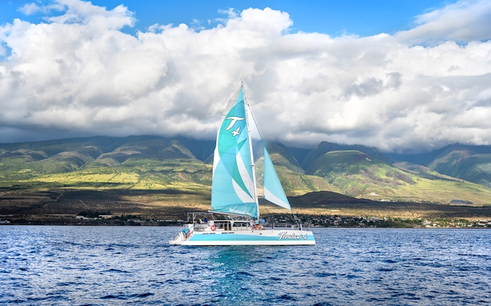 Sailboat on Luxury West Snorkel Sail Tour in Maui, Hawaii with lush mountains in the background.