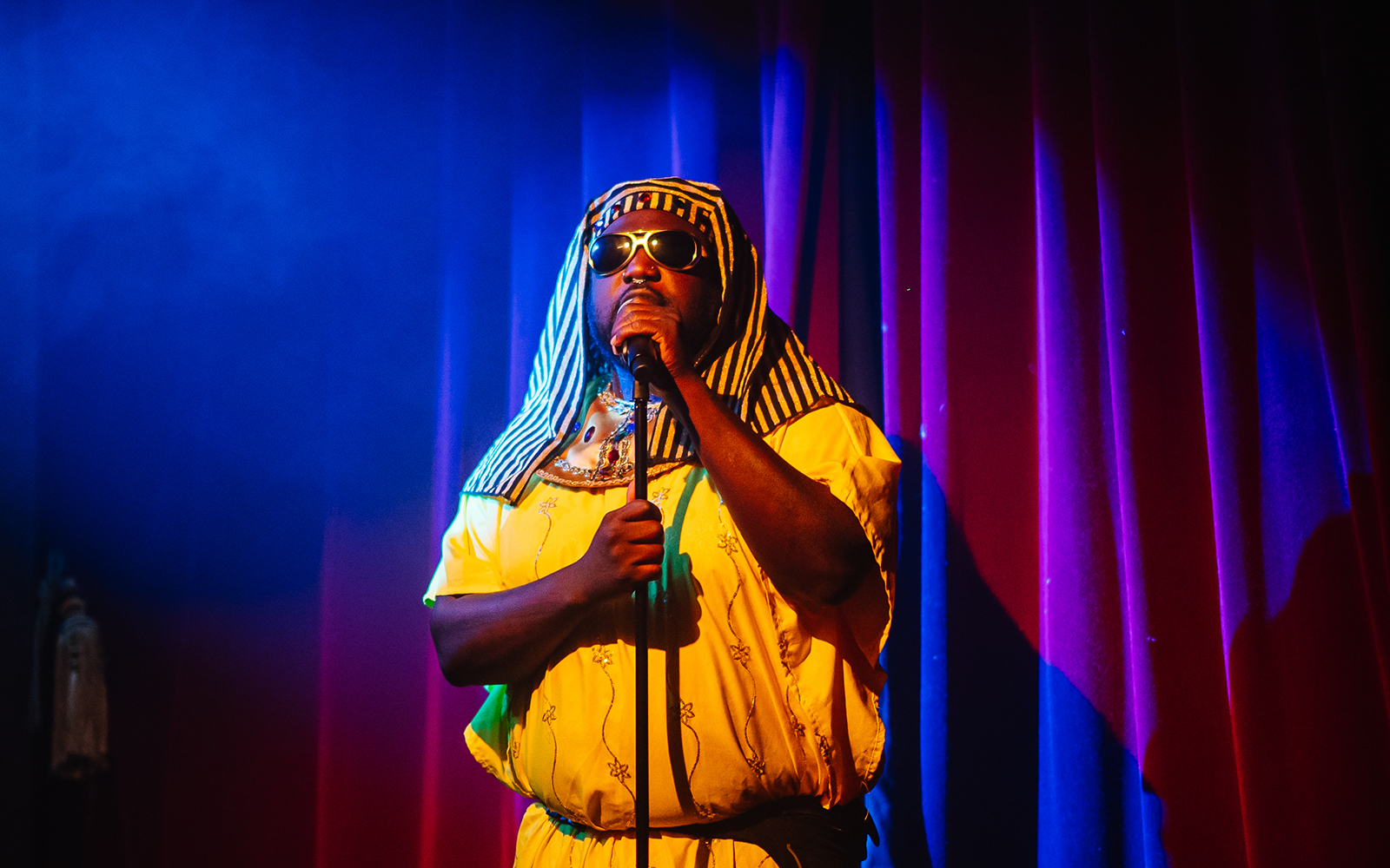 Performer in costume on stage at Miss Behaves: Maverick's Variety Show.