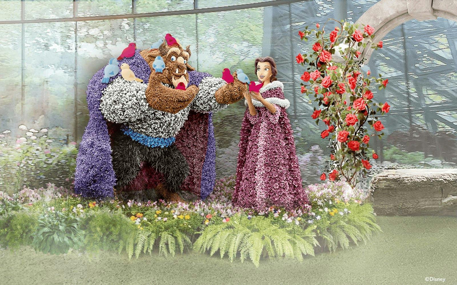 Belle and Beast topiary display with birds in a garden setting.