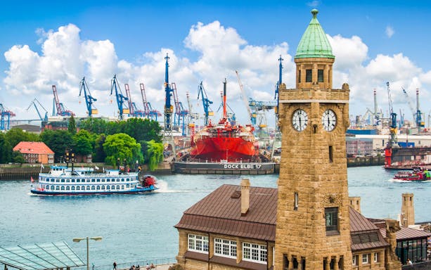 Clock tower and ships at Port of Hamburg with cranes in the background.