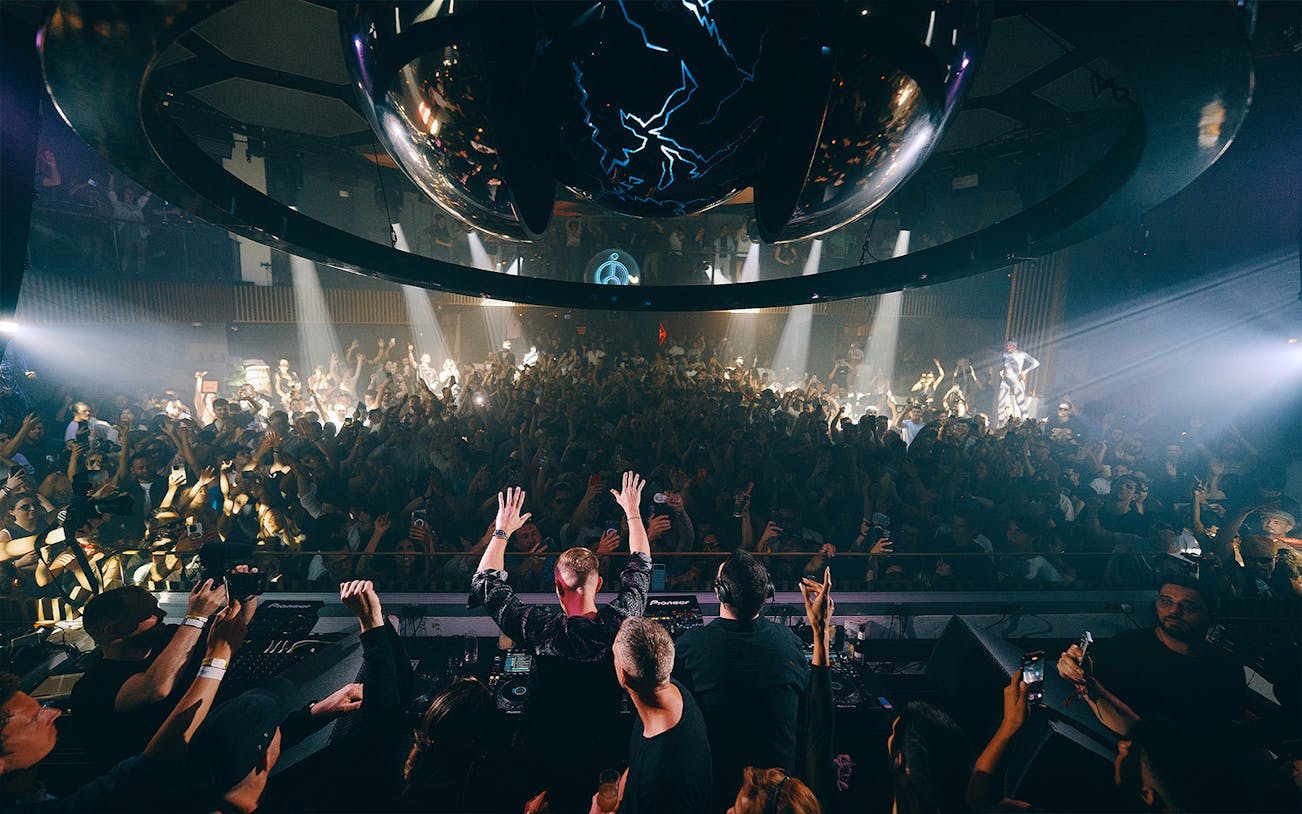 DJ performing at Camelphat event, Pacha Ibiza, with crowd dancing under club lights.