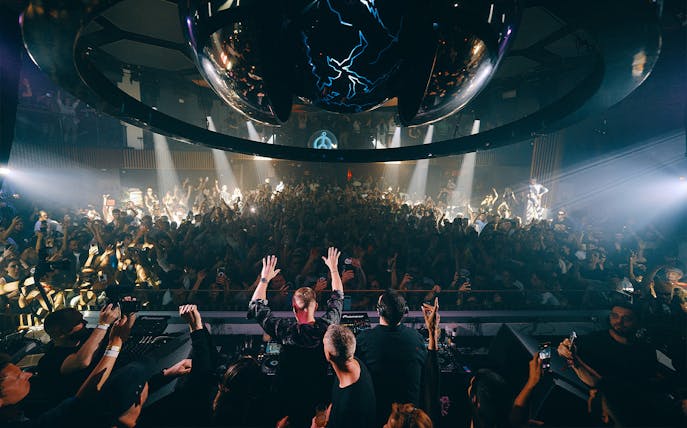 DJ performing at Camelphat event, Pacha Ibiza, with crowd dancing under club lights.