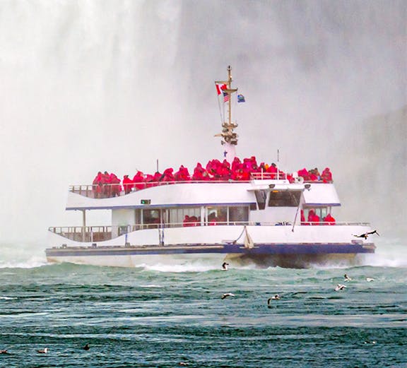 Hornblower cruise boat near Niagara Falls with passengers in red ponchos.