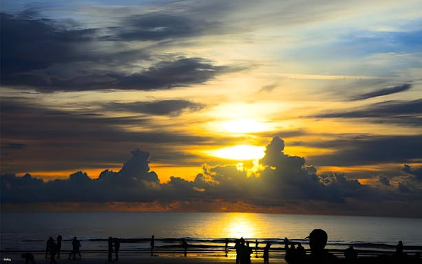 Sunset over the ocean with silhouettes of people on the beach, Kawa Kawa Fireflies & Sunset Cruise.