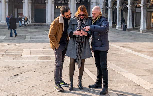 Tourists examining a map on a smartphone during a photo walking experience in Venice.