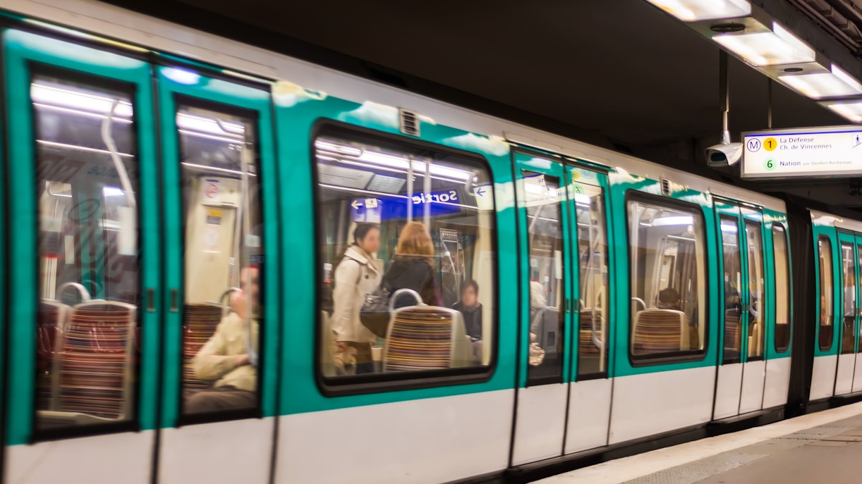 Paris Metro train arriving at a station with passengers boarding, Paris, France.