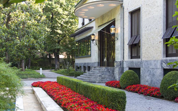Villa Necchi Campiglio entrance with garden path and red flowers.