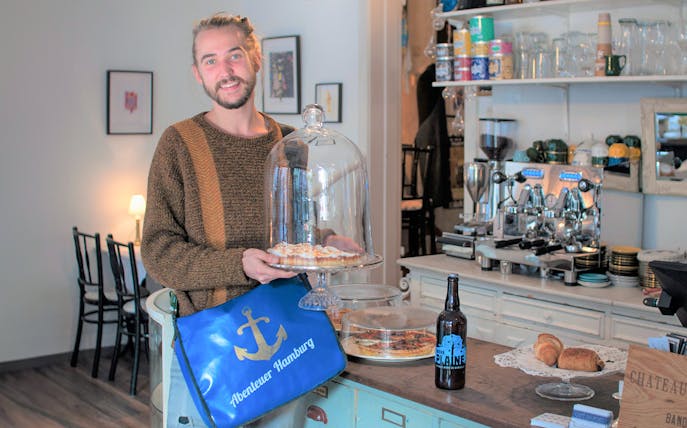 Man holding a dessert tray in a St. Pauli café during a guided culinary food tour.