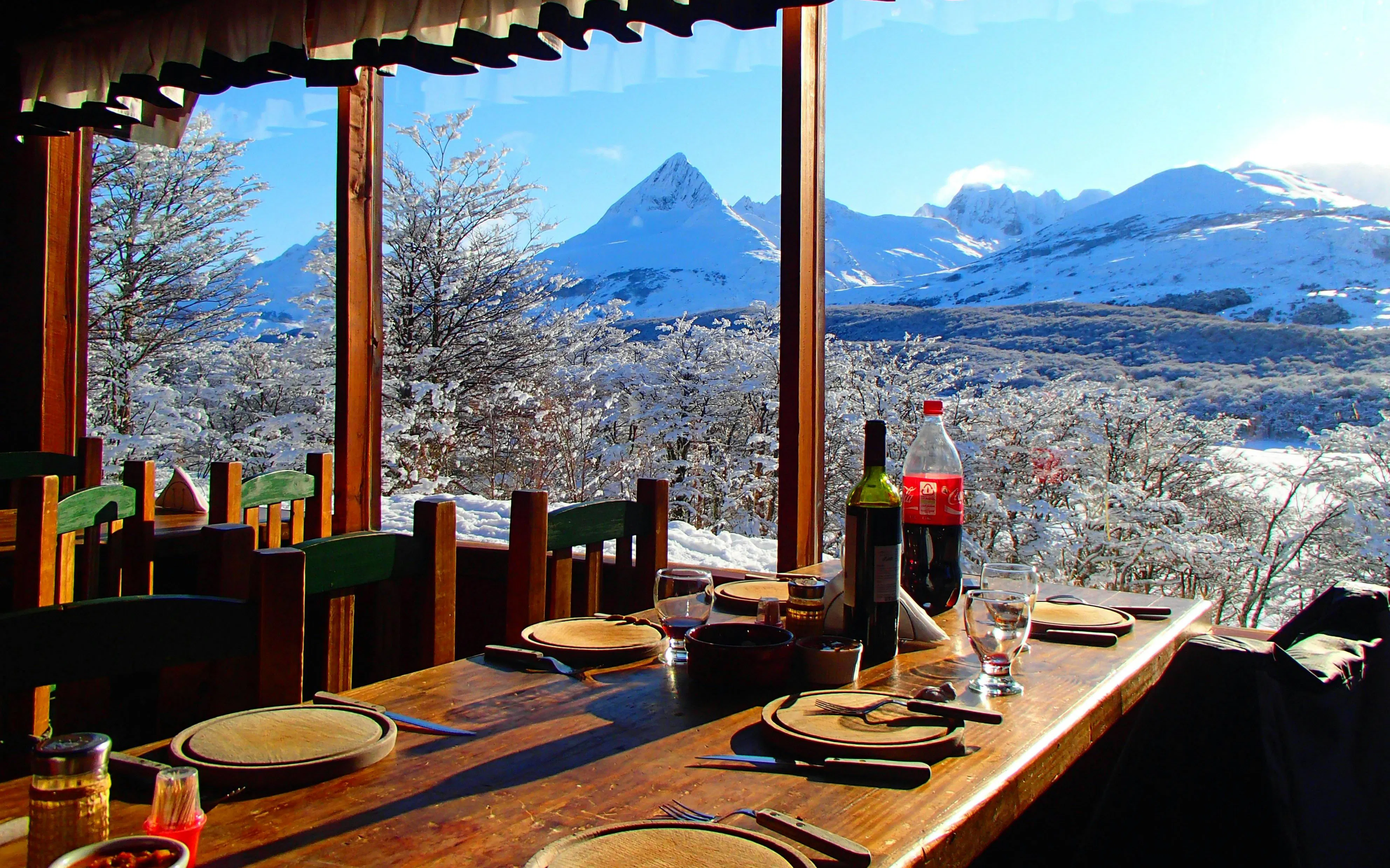 Dining table with wine and soda overlooking snowy mountains during Snow and Fire Night experience.