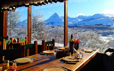 Dining table with wine and soda overlooking snowy mountains during Snow and Fire Night experience.