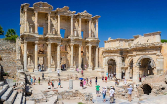 Celsus Library facade with tourists exploring Ephesus ruins, Turkey.