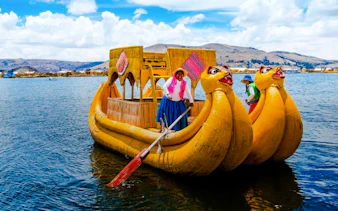 Traditional reed boat on Lake Titicaca with locals, Uros Floating Islands, Puno.